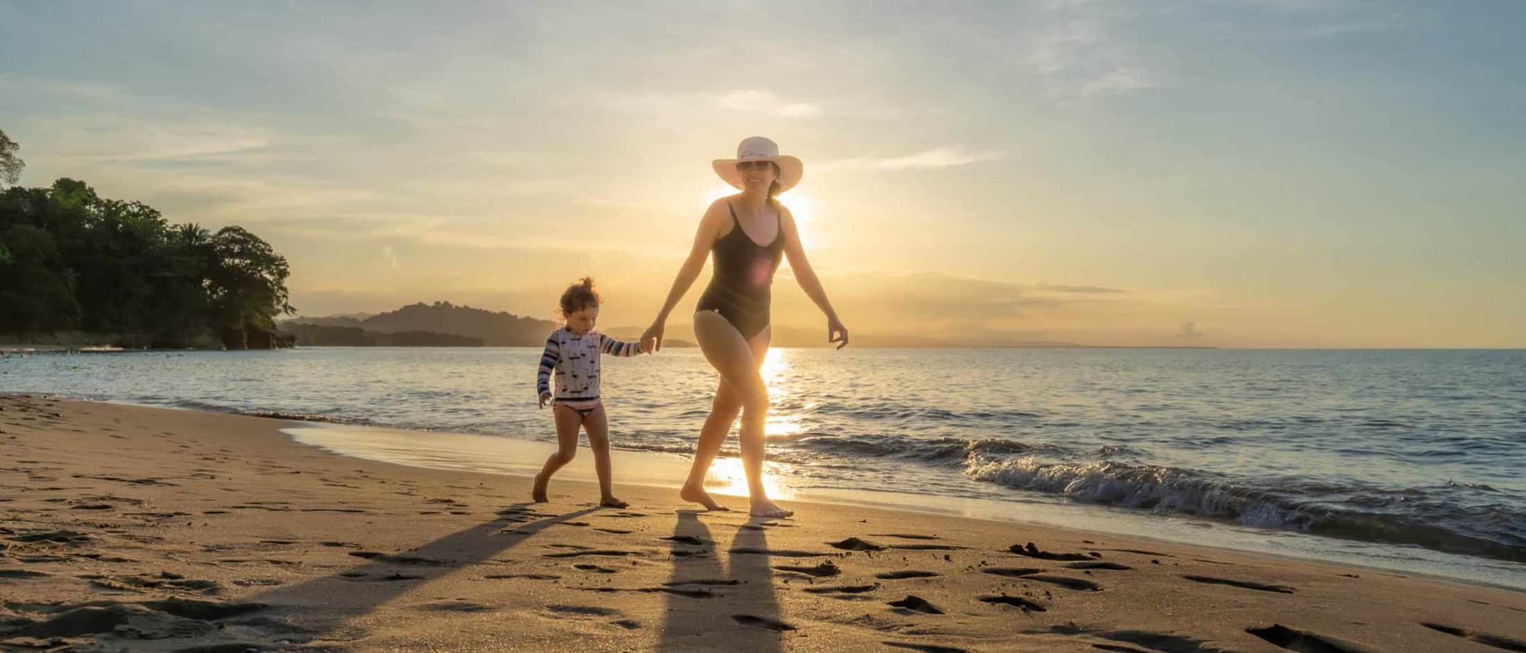 Une mère et son enfant sur la plage au coucher du soleil