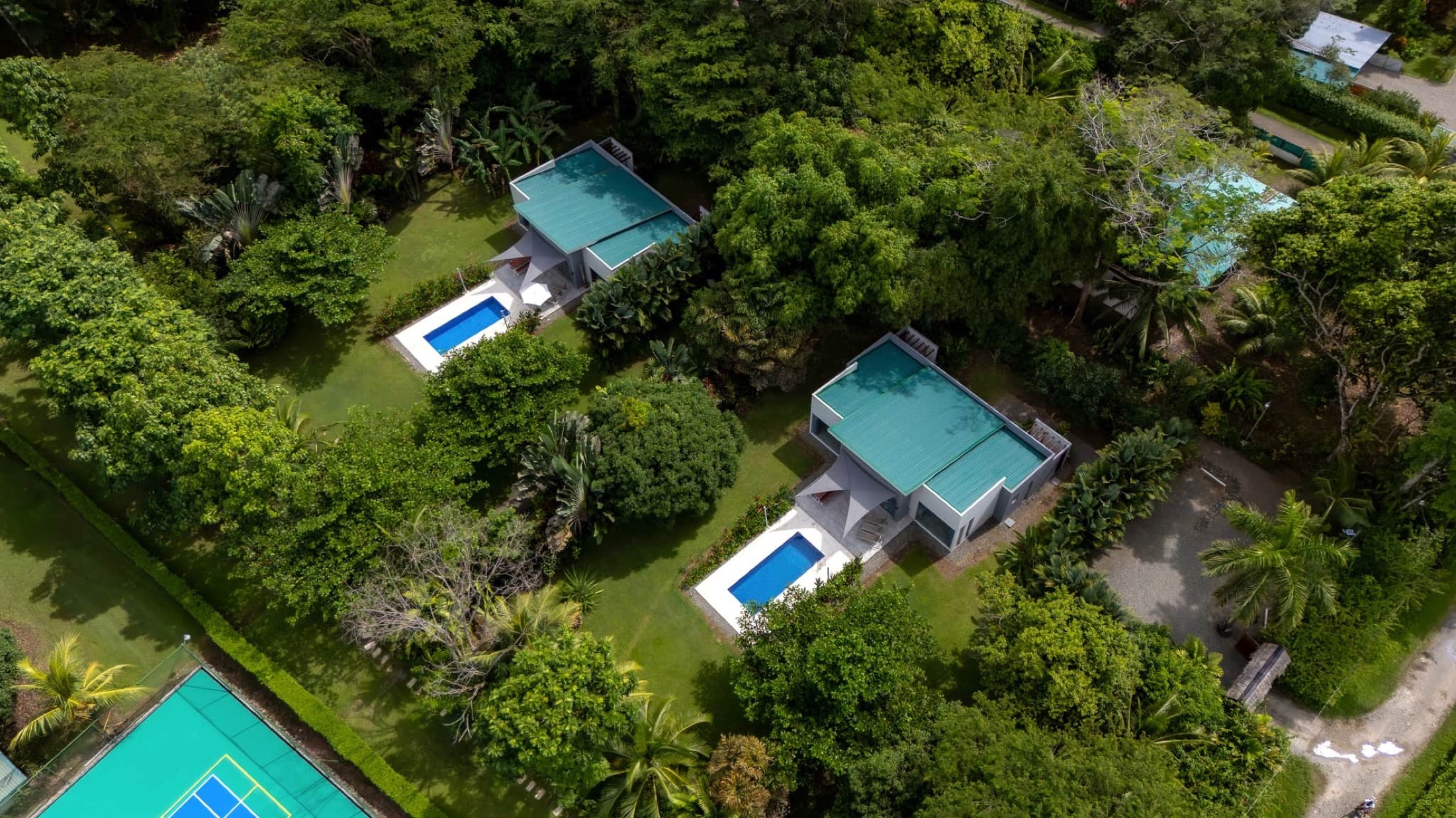 Les deux villas et leurs piscines vues du ciel, au milieu de la forêt
